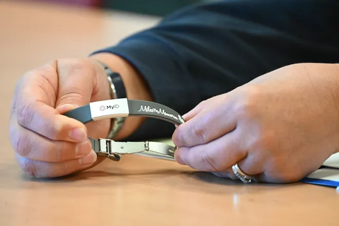 A person holding a medical ID bracelet demonstrating how to use it.
